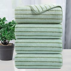 a stack of towels sitting on top of a table next to a potted plant