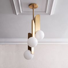 three white balls are hanging from a brass fixture in a room with beige walls and ceilings