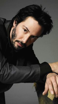 a man leaning on top of a wooden table with his hand on the ground and looking at the camera