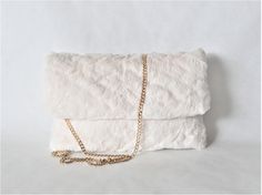 Faux fur clutch bag with removable golden chain. Off white clutch bag very pretty for bride at any season. Two links ended by a little golden ring can be outside. If you fix on them the hooks of the golden chain, the clutch becomes a little crossbody bag or shoulder bag! The soft and the silky fur make it very chic and fashion. This padded faux fur gives new style to a classic accessory, but useful and often indispensable to complete an up dressed outfit, cocktail, party... It's an unique item. White Pouch Clutch For Events, Elegant Evening Bags With Faux Fur Lining, White Evening Clutch Pouch, Luxury White Clutch With Removable Pouch, White Clutch With Gold-tone Hardware For Evening, White Evening Bag With Gold-tone Hardware, Elegant Faux Fur Bags, Bride Clutch, Fur Clutch Bag