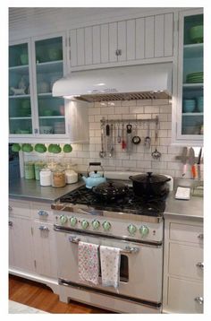 a stove top oven sitting inside of a kitchen next to white cupboards and drawers