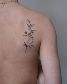 the back of a woman's shoulder with a small tattoo of flowers on it