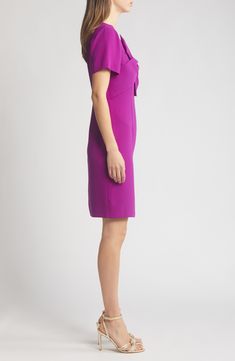 Be ready for your next evening event in this svelte sheath dress fashioned with an oversized bow at the bodice and a face-framing V-neckline. 38" length (size 6) V-neck Short sleeves Lined 100% polyester Dry clean Imported Formal Dresses With Bow And Straight Neckline, Fitted Dress With Bow And Asymmetrical Neckline, Formal Dress With Bow And Asymmetrical Neckline, Structured Cocktail Dress, Elegant Dress With Asymmetrical Neckline And Bow, Elegant Purple Dress With Straight Neckline, Elegant Dress With Bow And Asymmetrical Neckline, Elegant Dresses With Bow And Asymmetrical Neckline, Formal Knee-length Dresses With Bow