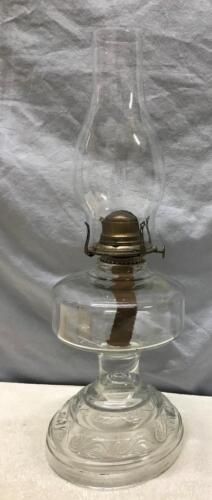 an old fashioned glass oil lamp on a white tableclothed background, with a small metal hook in the top