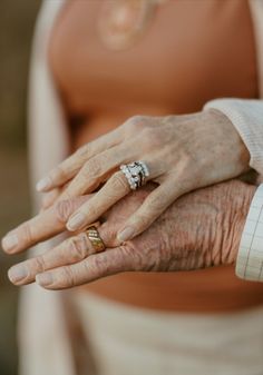 an older woman holding the hand of a younger man with two wedding rings on their fingers