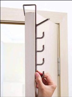 a person is opening a door with a coat rack attached to the side of it