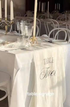 the table is set with white linens and place settings for guests to sit at