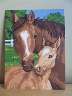 a painting of two brown horses standing next to each other on a wooden table in front of a white wall