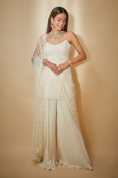 White kurta with beaded hand embroidered jaal. Comes with pleated sharara and a dupatta.
Components: 3
Pattern: Hand embroidered
Type Of Work: Beads
Neckline: Round
Sleeve Type: Sleeveless
Fabric: Georgette, Tulle
Color: White
Other Details: 
Embroidered dupatta
Occasion: Mehendi and Haldi,Sangeet - Aza Fashions Lehenga With Kurta, White Traditional Outfits For Women, White Sharara Outfit, White Haldi Outfit For Bride, White Suit Indian, Urbanic Outfit, White Ethnic Wear, Palazzo Styling, White Sharara Suit