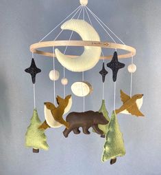 an animal mobile with stars and moon hanging from it's sides on a gray background