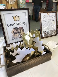 two framed pictures and some paper cut outs in a wooden box on a white table cloth