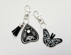 two black and white butterfly shaped keychains with tassels attached to them