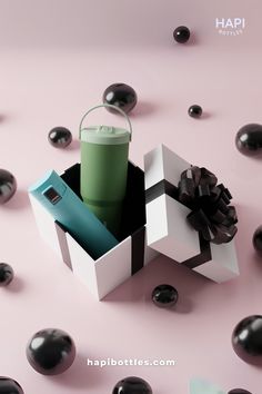 a green cup sitting inside of a white box on top of black rocks and water droplets