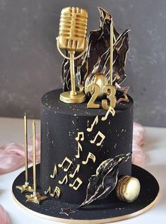 a black cake with gold decorations and a microphone