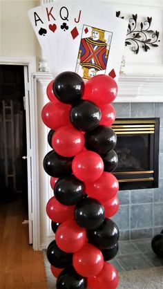 black, red and white balloons in front of a fireplace with playing cards on it