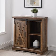 a small wooden cabinet with sliding doors and a vase on the shelf next to it