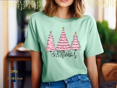 Trio of Pink Christmas Trees, Tee Shirt. This shirt is perfect for all ages and is available in many sizes. Girls, ladies, women, Mom, Grandma,  Sister, will all look and feel comfortable in this premium Bella & Canvas Tee- Shirt printed in high quality inks with this Christmas design. Holiday shirt, Santa time, Pink Era, Happy Girl shirt 🌸 Welcome to TarryTown Goods🌸 Elegantly casual Tee This comfortable unisex Tee shirt will be yours and your friends' new favorite tee. Soft cotton and quality print make users fall in love with it over and over again. These t-shirts have-ribbed knit collars to bolster shaping. The shoulders have taping for better fit over time.  Be simple, be different! M A T E R I A L S → 4.2 oz./yd², 52/48 airlume combed and ring-spun cotton/polyester, 32 singles → At Pink Graphic Print T-shirt For Holiday, Cute Holiday T-shirt With Short Sleeves, Cute Pink Christmas Tops, Cute Pink Holiday Tops, Cute Pink Holiday Top, Cute Pink Top For Holiday, Cute Pink Christmas T-shirt, Pink Holiday T-shirt With Short Sleeves, Pink Short Sleeve Holiday T-shirt