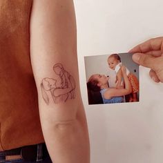 a woman with a small tattoo on her arm holding up a baby's photo