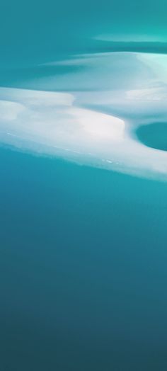 an airplane flying over the ocean with white clouds in the sky and blue water below