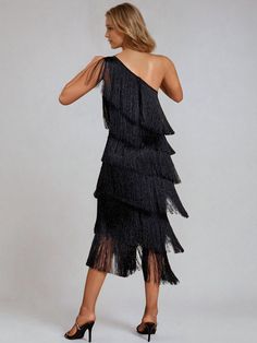 a woman wearing a black dress with fringes on the skirt and one shoulder, back view