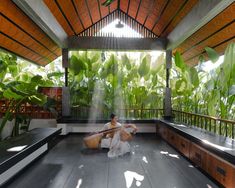 a woman sitting on the floor in front of a plant filled room with lots of green plants