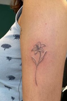 a woman's arm with a small flower tattoo on the left side of her arm