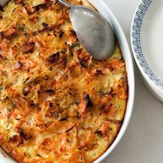 a casserole dish is shown with a spoon in it and two plates are next to it