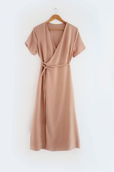 a dress hanging up on a hanger in front of a white wall with a wooden hanger