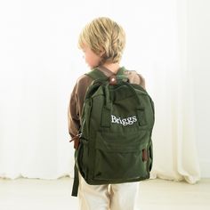 a young boy wearing a green backpack with the word bags on it