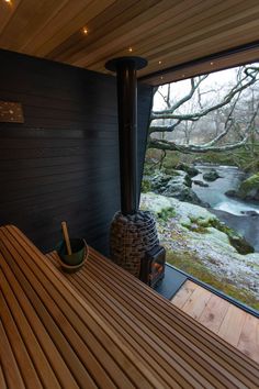 a wooden table sitting in front of a window next to a forest filled with trees