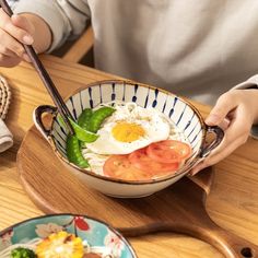 a person sitting at a table with a bowl of food in front of them and chopsticks sticking out of the bowl