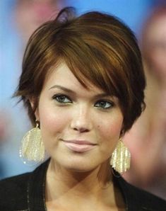 a close up of a person with short hair and earrings on her head, looking at the camera