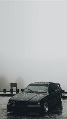 a black car parked on the side of a road in the rain