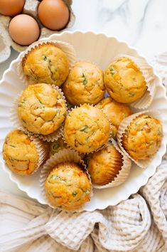 some muffins are on a white plate next to eggs