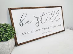 a wooden sign that says be still and know that i am god on it next to a potted plant