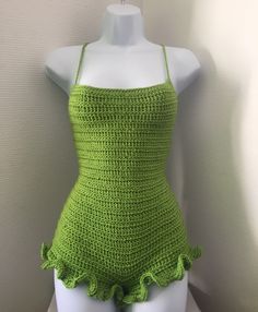 a green crochet swimsuit on display in front of a white mannequin