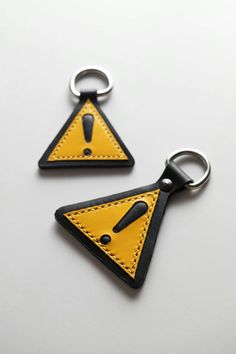 two triangle shaped key chains with black and yellow stitching