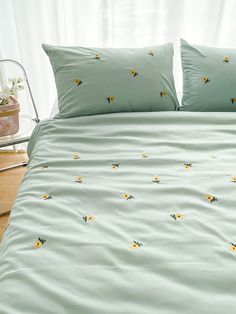 a bed with green sheets and yellow flowers on it