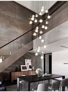 an elegant dining room with glass chandelier and black table in front of stairs