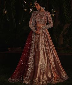 a woman in a red and gold lehenga standing on the grass at night