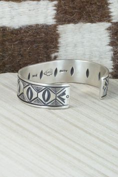 This sterling silver bracelet was made by Navajo silversmith Calvin Martinez. The inside is signed C MTZ, Navajo and stamped sterling.Size: 5 3/8" (will fit up to a 6 3/8" wrist)Gap: 1"Width: 5/8"Free shipping on all orders! We ship with USPS and always include tracking. All orders ship within a day of payment.Returns are accepted up to 30 days after you receive your order. Just send us a message. Our shop offers cash back or store credit. The item must be returned in new condition. Southwestern Silver Cuff Bracelet With Inlay, Southwestern Sterling Silver Stamped Bangle Bracelet, Southwestern Style Stamped Sterling Silver Bangle Bracelet, Southwestern Style Etched Sterling Silver Bracelet, Southwestern Style Stamped Sterling Silver Bangle, Artisan Sterling Silver Bracelet With Inlay, Southwestern Sterling Silver Bracelet, Sterling Silver Southwestern Bracelet, Sterling Silver Bracelet