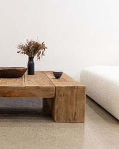 a wooden table with two bowls on it and a vase full of flowers in the middle