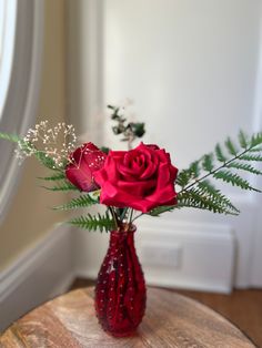 a vase filled with red roses on top of a wooden table