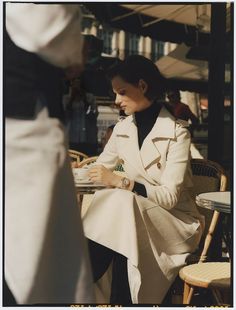 a woman sitting at a table reading a book