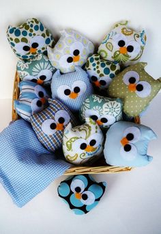 a basket filled with stuffed owls sitting on top of a blue blanket