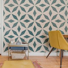 two chairs and a table in front of a wall with geometric designs on it,