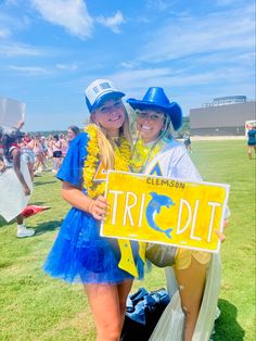 two women in costumes pose for a photo while holding a sign that says trick out