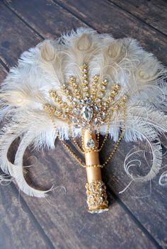 a white and gold feather bouquet on a wooden table with an ornament in the center