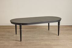 an oval table with black legs on a wooden floor