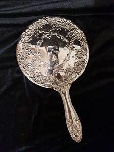 a silver spoon with a skull on it sitting on a black cloth covered tablecloth